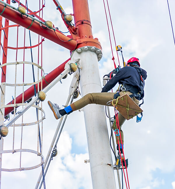 Técnico de manutenção industrial escalando e trabalhando em altura com equipamento de segurança.